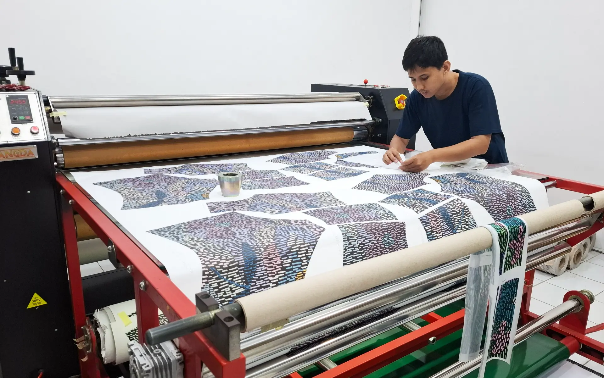 Printed swim fabric panels moving through the heat press at the Bali Swim print studio